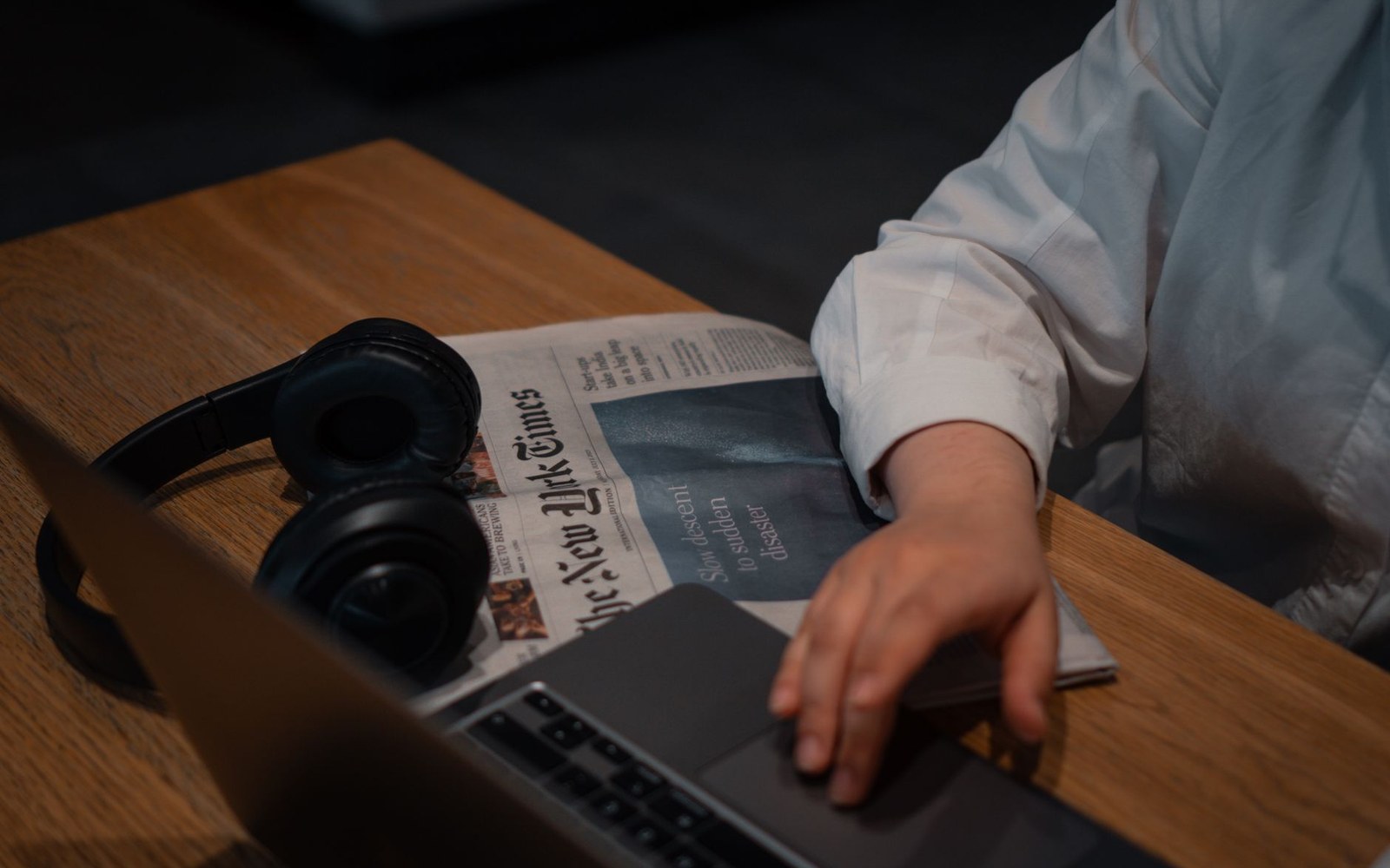 Adult leaning over a laptop showing a Feedly unread list several hundred items long, desk lamp casting warm light on the screen